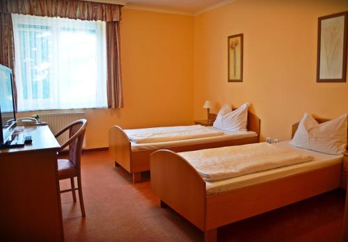 Habitación de hotel con 2 camas y escritorio en Hotel Weldi, en Győr