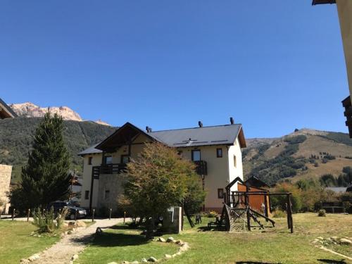 a house in a field with mountains in the background at Departamento Piedra del Condor in San Carlos de Bariloche