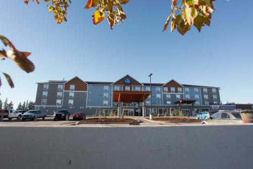 a large building with cars parked in a parking lot at Pomeroy Inn & Suites at Olds College in Olds