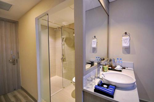 La salle de bains est pourvue d'un lavabo et d'une douche en verre. dans l'établissement The MCR Luxury Nha Trang, à Nha Trang