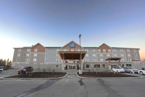 a large hotel with a parking lot in front of it at Pomeroy Inn & Suites at Olds College in Olds