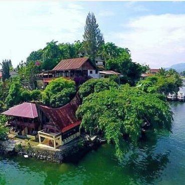 a house on an island in the water at Reggae Guest House in Tuk Tuk