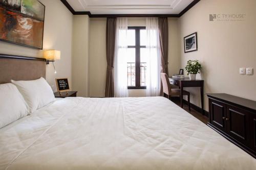 a bedroom with a large white bed and a desk at CityHouse - Atelier Apartment & Hotel in Ho Chi Minh City