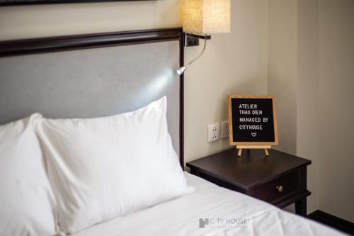 a bedroom with a bed and a sign on a night stand at CityHouse - Atelier Apartment & Hotel in Ho Chi Minh City