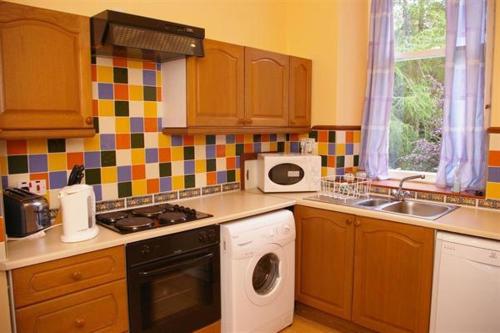 cocina con lavadora y fregadero en The Maid's House, en Lanark