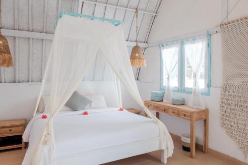 a bedroom with two beds and a table and windows at 7SEAS Cottages in Gili Islands