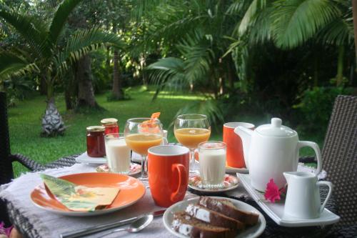 una mesa con platos de comida y vasos de zumo de naranja en CHAMBRES LEZARD Home en Païta