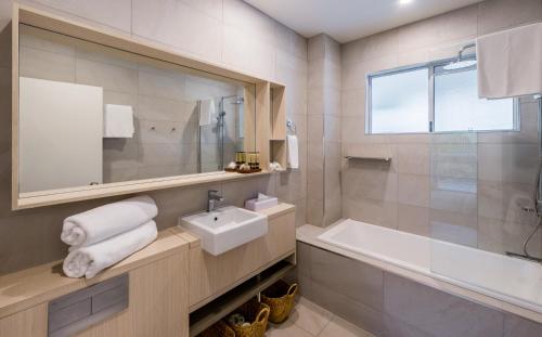 a white bathroom with a sink and a bath tub at Coral Coast Resort Accor Vacation Club Apartments in Palm Cove