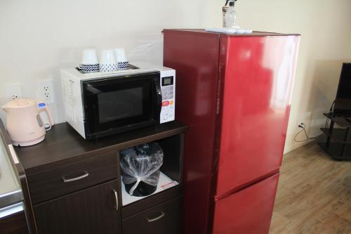 a microwave and a red refrigerator in a kitchen at Gate Inn Nago in Nago