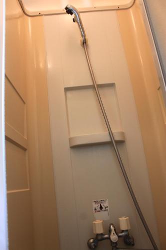 eine Badezimmerkabine mit einer Pfeife an der Wand in der Unterkunft Farm Inn Tsurui in Tsurui