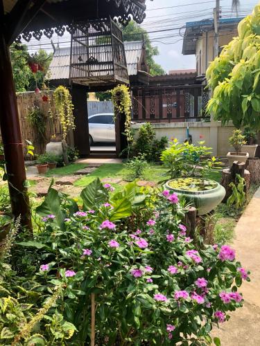 a garden with pink flowers and a bird cage at Banthai Guesthouse in Phetchaburi