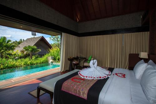 a bedroom with a bed with a view of a pool at Sanctoo Suites & Villas in Gianyar