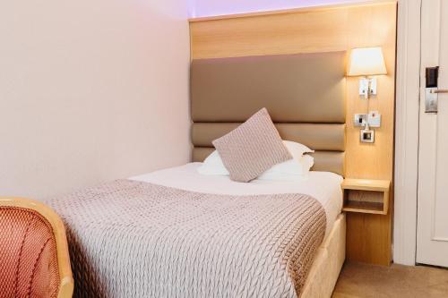 a small bedroom with a bed with a headboard at Crown Spa Hotel Scarborough by Compass Hospitality in Scarborough