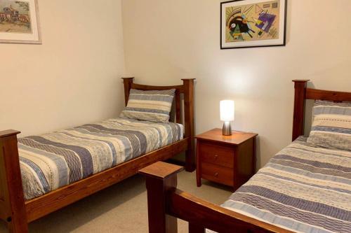 ein Schlafzimmer mit 2 Betten und einer Lampe auf einem Nachttisch in der Unterkunft Leeward 'tranquil beachfront' in Kingscote