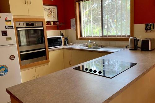 a kitchen with a counter with a sink and a refrigerator at Leeward 'tranquil beachfront' in Kingscote