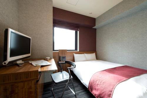 a bedroom with a bed and a desk with a television at Hotel Villa Fontaine Tokyo-Shinjuku in Tokyo