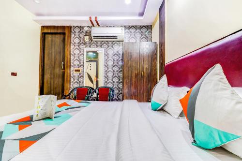 a bedroom with a large white bed with colorful pillows at FabHotel Gazal Residency Mahanagar in Lucknow