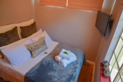 a small bedroom with a bed with towels on it at On Pinewood Guest House in Cape Town