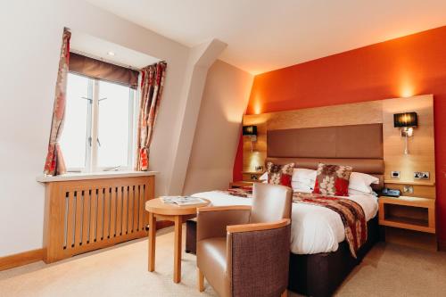 a hotel room with a bed and a desk and a table at Crown Spa Hotel Scarborough by Compass Hospitality in Scarborough