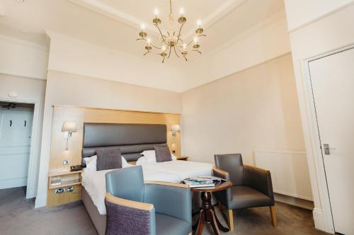a hotel room with a bed and a table and chairs at Crown Spa Hotel Scarborough by Compass Hospitality in Scarborough