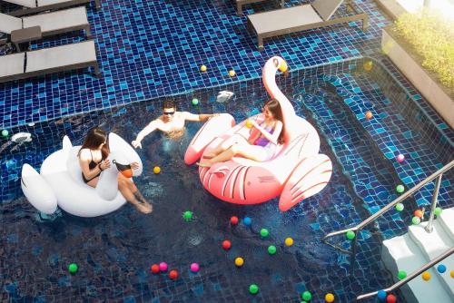 a group of people in a swimming pool with inflatable flamingos at Eleven Hotel Bangkok Sukhumvit 11 in Bangkok