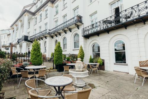 a patio with tables and chairs in front of a building at Crown Spa Hotel Scarborough by Compass Hospitality in Scarborough