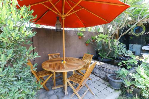 einen Holztisch und Stühle unter einem Sonnenschirm in der Unterkunft Ninja Suite Villa in Denpasar