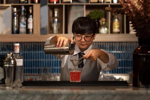 a man is making a drink in a bar at Eleven Hotel Bangkok Sukhumvit 11 in Bangkok