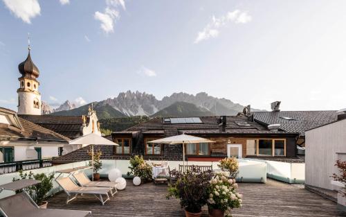 a patio with chairs and umbrellas on top of a building at Boutique & Gourmet Hotel Orso Grigio in San Candido