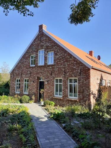 a brick house with a pathway in front of it at Pilsumer Warfthaus in Krummhörn