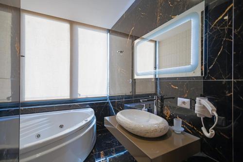 a bathroom with a tub and a toilet and a sink at Brilliant Hotel & SPA in Golem