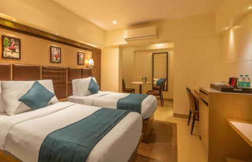 a hotel room with two beds and a desk at Hotel Oriental Aster - Mumbai International Airport in Mumbai