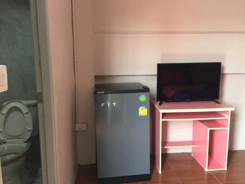 a small bathroom with a toilet and a tv on a desk at SMILE HOME GUESTHOUSE in Rayong