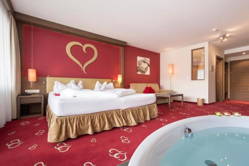 a hotel room with a large bed and a bath tub at Alpen-Herz Romantik & Spa - Adults Only in Ladis