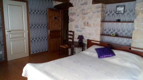 a bedroom with a bed with a purple pillow on it at Chambres d'hôtes - Domaine Beau Sejour in Biaudos