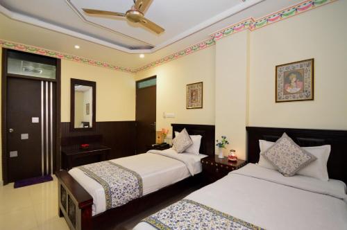 a hotel room with two beds and a mirror at Hotel Surya Garh in Jaipur