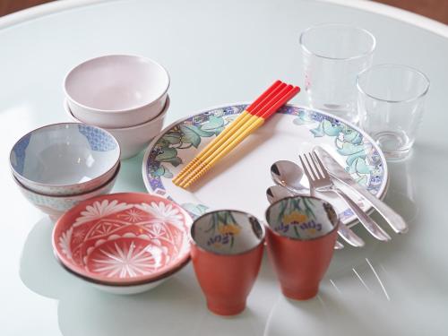 a white table with a plate and bowls and utensils at Yomitan Condhotel ND in Yomitan