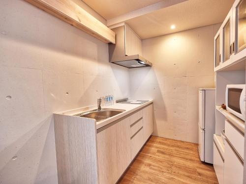 a kitchen with a sink and a refrigerator at Yomitan Condhotel ND in Yomitan