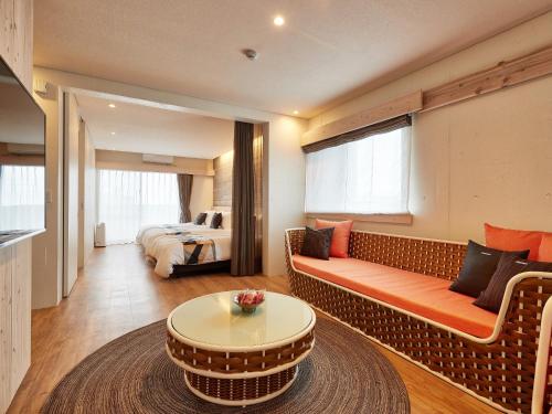 a room with a couch and a table and a bed at Yomitan Condhotel ND in Yomitan