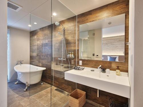 a bathroom with a tub and a sink and a mirror at Yomitan Condhotel ND in Yomitan