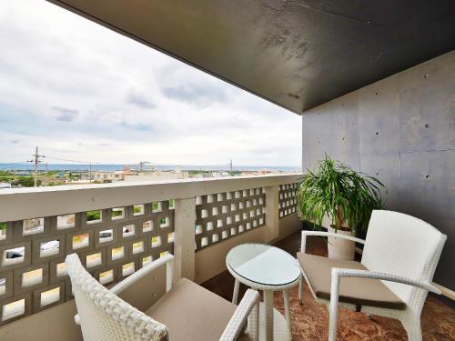 a balcony with chairs and a table and a view at Yomitan Condhotel ND in Yomitan