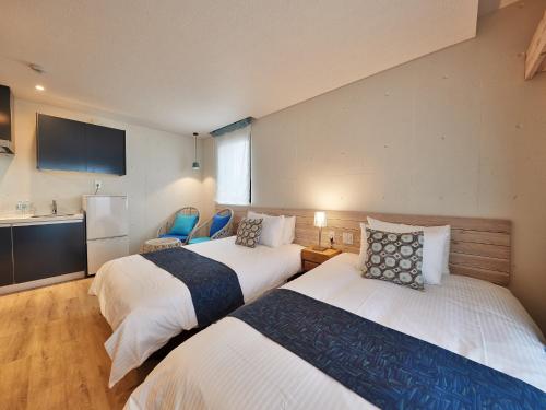 a hotel room with two beds and a kitchen at Yomitan Condhotel ND in Yomitan