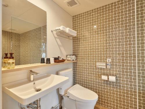 a bathroom with a sink and a toilet and a mirror at Yomitan Condhotel ND in Yomitan