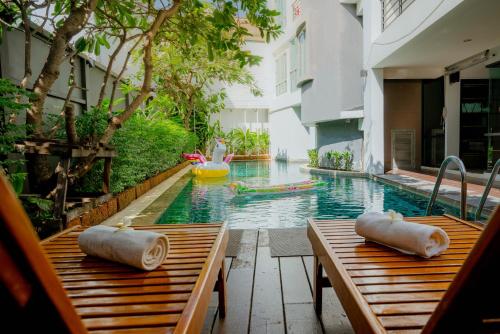 a pool with two wooden tables and a pool float at Peace Land Khaosan in Bangkok