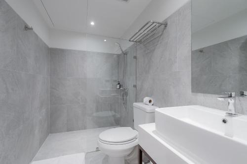 a white bathroom with a toilet and a sink at True Siam Phayathai Hotel in Bangkok