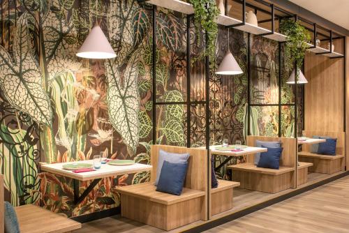 a restaurant with tables and chairs in front of a colorful wall at ibis Styles Kraków East in Kraków