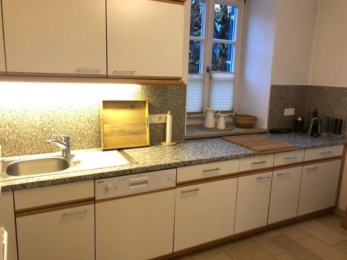 a kitchen with white cabinets and a sink at Ferienwohnung Eiskögerl im Barbarahof in Bischofshofen