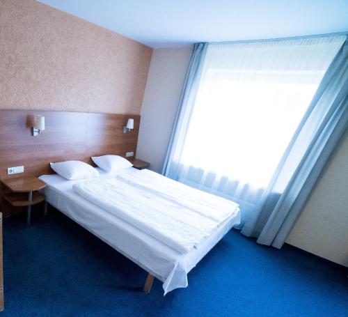 a bedroom with a bed and a large window at Hotel Tigra in Priekuļi