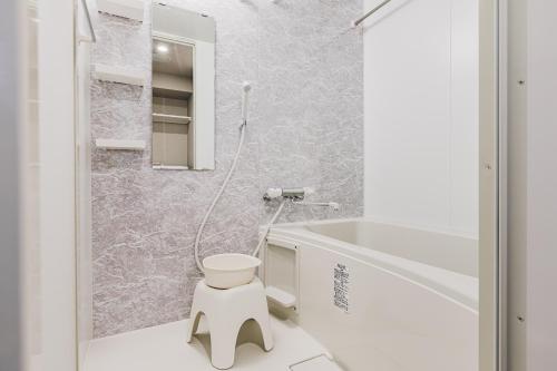 a white bathroom with a toilet and a sink at Ostay Shin-Osaka Hotel Apartment in Osaka