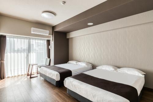 a hotel room with two beds and a window at Ostay Shin-Osaka Hotel Apartment in Osaka